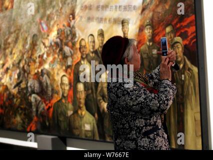 Ein Besucher nimmt Fotos eines Öl Malerei in Gedenken an das Massaker von Nanjing in der Provinz Jiangsu Art Museum in Nanjing City, East China Jian Stockfoto