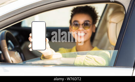 Happy afro Frau im Auto zeigt Smartphone mit leerer Bildschirm Stockfoto