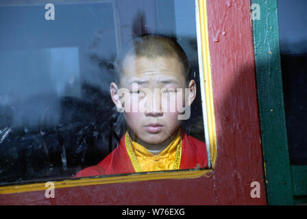 Ein Anfänger Mönch aus dem Fenster blickt nachdenklich im Gandan Kloster in Ulan Bator Stockfoto