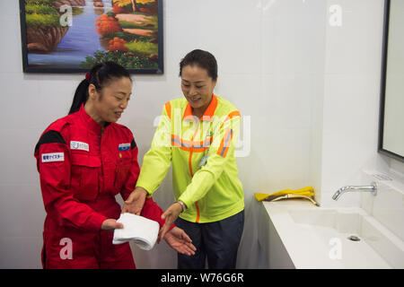 Japanische Reinigung Arbeitnehmer Haruko Niitsu, Links, lehrt eine chinesische Reiniger in eine Toilette an der Shenzhen Bahnhof Nord in Shenzhen City, South China Stockfoto