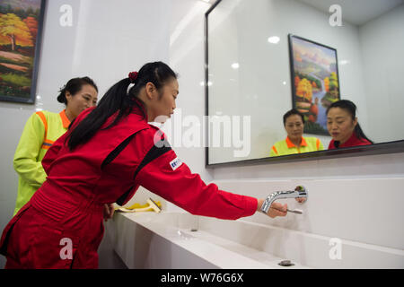 Japanische Reinigung Arbeitnehmer Haruko Niitsu, front, lehrt eine chinesische Reiniger in eine Toilette an der Shenzhen Bahnhof Nord in Shenzhen City, South China Stockfoto
