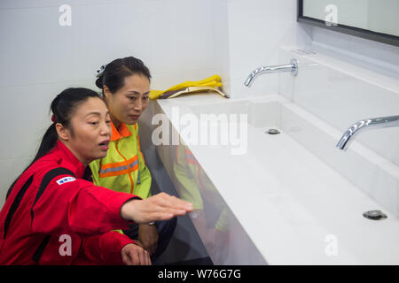 Japanische Reinigung Arbeitnehmer Haruko Niitsu, front, lehrt eine chinesische Reiniger in eine Toilette an der Shenzhen Bahnhof Nord in Shenzhen City, South China Stockfoto