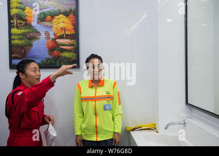 Japanische Reinigung Arbeitnehmer Haruko Niitsu, Links, lehrt eine chinesische Reiniger in eine Toilette an der Shenzhen Bahnhof Nord in Shenzhen City, South China Stockfoto