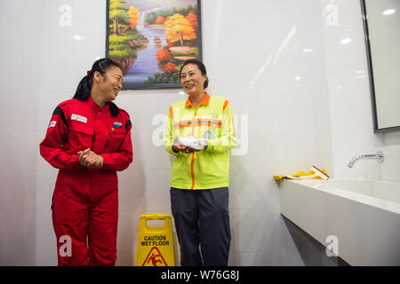 Japanische Reinigung Arbeitnehmer Haruko Niitsu, Links, Gespräche mit einem chinesischen Reiniger in eine Toilette an der Shenzhen Bahnhof Nord in Shenzhen City, South China Stockfoto