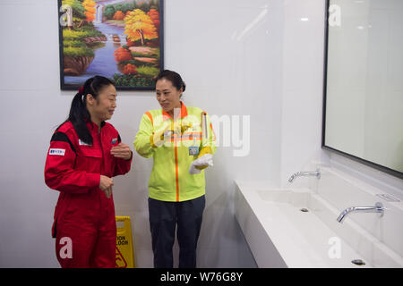 Japanische Reinigung Arbeitnehmer Haruko Niitsu, Links, lehrt eine chinesische Reiniger in eine Toilette an der Shenzhen Bahnhof Nord in Shenzhen City, South China Stockfoto