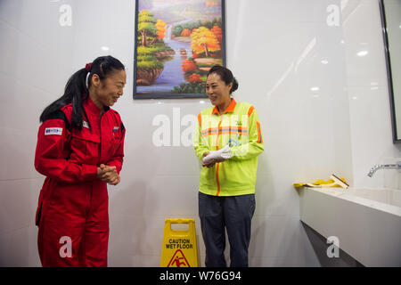 Japanische Reinigung Arbeitnehmer Haruko Niitsu, Links, Gespräche mit einem chinesischen Reiniger in eine Toilette an der Shenzhen Bahnhof Nord in Shenzhen City, South China Stockfoto