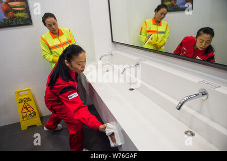 Japanische Reinigung Arbeitnehmer Haruko Niitsu, front, lehrt eine chinesische Reiniger in eine Toilette an der Shenzhen Bahnhof Nord in Shenzhen City, South China Stockfoto
