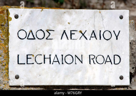 Griechenland. Antike Korinth. Zweisprachige Inschrift in griechischer und englischer Sprache, hinsichtlich der Lechaion Straße. Marmor gepflasterte Straße zum Hafen von Lechaion. Peloponnes. Stockfoto