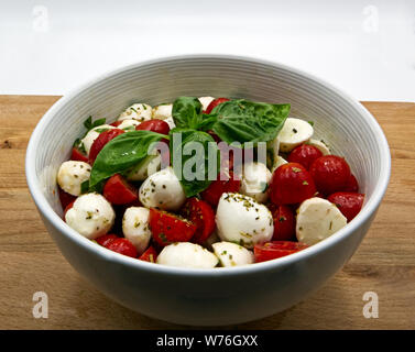 Mozzarella und Tomaten auf schwarzem Schiefer. Öl, origan und Petersilie Stockfoto