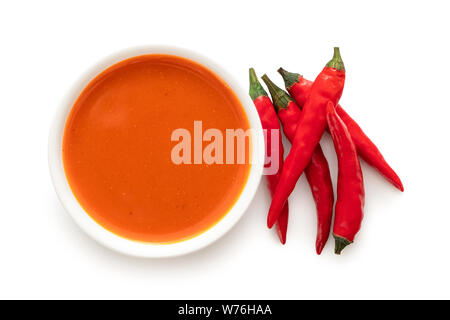 Peri Peri Chili Sauce in einem weißen Keramik Schüssel neben einem Haufen rote Chilis auf weiß von oben isoliert. Stockfoto