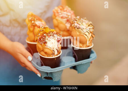Vier Hong Kong Waffeln in cups Essen Lieferung in der Hand der Frau Stockfoto