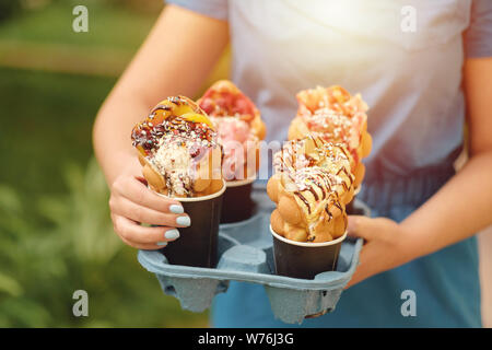 Vier Hong Kong Waffeln in cups Essen Lieferung in der Hand der Frau Stockfoto