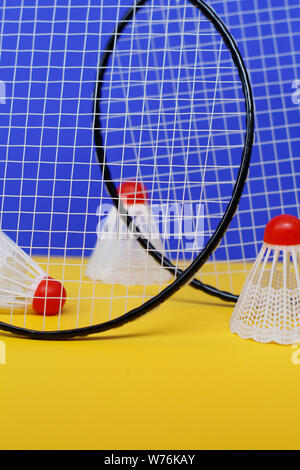 Badminton. Drei Bälle und zwei Badminton Schläger. Die farbigen Hintergrund ist blau und gelb. Idee für ein Magazin. Stockfoto