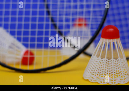 Badminton. Drei Bälle und zwei Badminton Schläger. Die farbigen Hintergrund ist blau und gelb. Idee für ein Magazin. Stockfoto