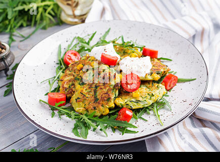 Zucchini Pfannkuchen mit Mais und saure Sahne serviert Rucola, Tomaten Salat. Stockfoto