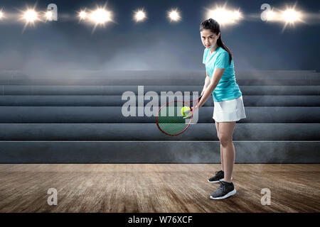 Asiatische Frau mit Tennisschläger und Ball in ihre Hände in die Position auf dem hallenplatz bereit Stockfoto