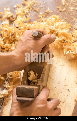 Holz- hand-Ebene. Nahaufnahme des woodworker Hände rasieren mit einem Flugzeug in einer Tischlerei Werkstatt Stockfoto