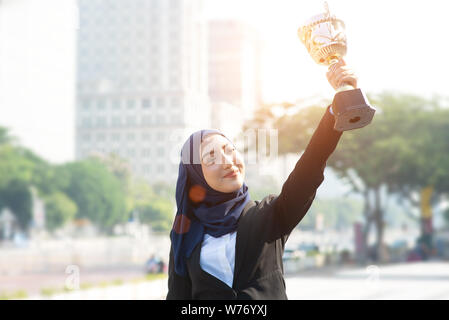 Muslimische Geschäftsfrau, die eine Trophäe, Frau macht in Business, top Performance Concept. Stockfoto