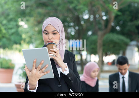 Muslimische business Frau trinkt Kaffee beim Gehen am Morgen zu arbeiten. Stockfoto