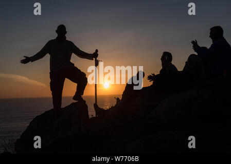 Pilger auf dem Kap Finisterre, der das Ende des Camino de Santiago in Spanien. Silhouette eines Mannes auf Felsen mit einem Spazierstock, wi Stockfoto