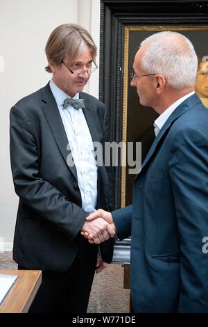 München, Deutschland. 05 Aug, 2019. Bernhard Maaz (l), Kunsthistoriker und Generaldirektor der Bayerischen Staatsgemäldesammlungen, schüttelt Hände mit Hardy Langer, Vertreter der Erbengemeinschaft, nach der Unterzeichnung des Vertrages über die Rückgabe. Fünf Gemälde, drei Farbe Gravuren und eine hölzerne Verkleidung wurde durch die Gestapo im November 1938 beschlagnahmt. Die Münchner Sammlungen haben nun die Werke an die Erben von Julius und Simone Davidsohn aus München zurück. Credit: Sina Schuldt/dpa/Alamy leben Nachrichten Stockfoto