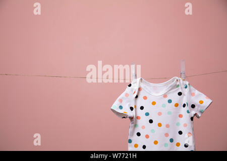 Cute Polka Dot Baby Body Anzug hängen von einer Linie gegen einen rosa Hintergrund Stockfoto