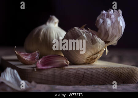 Köpfe von Knoblauch auf einem Schneidebrett Stockfoto