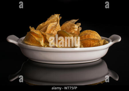 Menge ganze Frische orange Physalis in weiße, ovale Keramik Schüssel auf schwarzem Glas isoliert Stockfoto