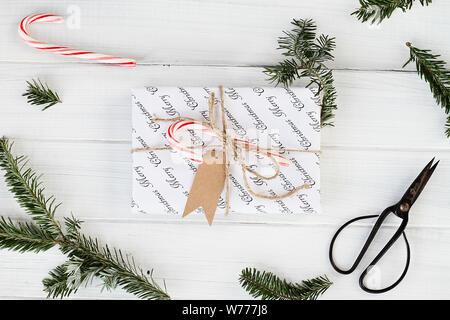 Schönes Weihnachtsgeschenk mit leeren tag. Natürlich mit zuckerstangen eingerichtet, Tannenbaum, Zweige und Garn über einen weißen Hintergrund mit Zuckerstangen. Ima Stockfoto