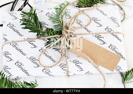 Schöne Weihnachtsgeschenke mit leeren tag. Natürlich mit Tannenbaum, Zweige und Garn über eine rustikale Hintergrund eingerichtet. Extrem flache Tiefenschärfe Stockfoto