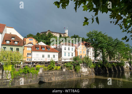 Ljubljana, Slowenien. 3. August 2019. Die Häuser auf der Ljubljanica Fluss mit der Burg im Hintergrund Stockfoto