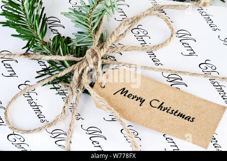 Schönes Weihnachtsgeschenk mit Variable, liest "Frohe Weihnachten." eingerichtet und natürlich mit Tannenbaum, Zweige und Garn. Stockfoto