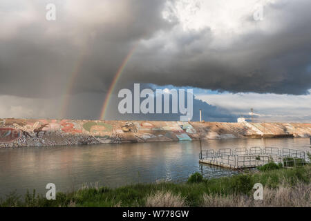 Einem recht ungewöhnlichen doppelten Regenbogen über dem ähnlich ungewöhnliche Deich am Arkansas River in Pueblo, Colorado, physische Beschreibung: 1 Foto: digital, tiff-Datei, Farbe. Hinweise: Erklärungen für dieses Phänomen sind am besten durch ein meteorologe vorgesehen, aber beachten Sie, dass die Reihenfolge der Farben in den beiden Regenbogen, von denen einer immer schwächer als die anderen umgekehrt wird. Mehr definiert der beiden scheint die skizzierte Kopf von den weisen Risse in Film und Fernsehen Komiker Groucho Marx zu steigen. Sein Bild ist ein Teil der langen und vielseitigen Wandbild auf der Deich Mauern, die zunächst als erschienen Stockfoto