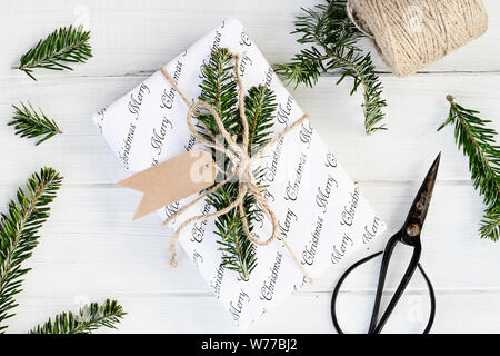 Weihnachten Geschenk mit leeren tag. Natürlich mit Tannenbaum, Zweige und Garn über einen weißen Hintergrund eingerichtet. Bild geschossen von Overhead. Stockfoto
