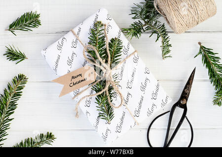 Urlaub Geschenk mit Frohe Weihnachten Tag. Natürlich mit Tannenbaum, Zweige und Garn über einen weißen Hintergrund eingerichtet. Bild geschossen von Overhead. Stockfoto