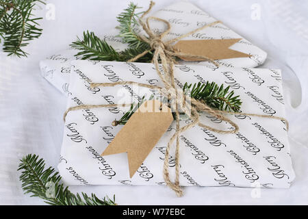Zwei schöne Weihnachtsgeschenke mit leeren tag. Natürlich mit Tannenbaum, Zweige und Garn über einen weißen Hintergrund eingerichtet. Extrem geringer Tiefe der fie Stockfoto