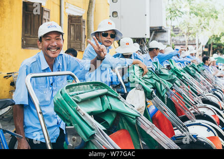 Hoi An, Vietnam - Juni 2019: Vietnamesische Rikscha lächelt und zeigt Frieden Zeichen mit der Hand Stockfoto