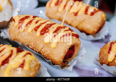 Hot Dog mit einer Scheibe Brot knusprig und weiche Creme mit geschmolzenem Käse und Ketchup sauce Toppings gefüllt. Selektive konzentrieren. Kopieren Sie Platz. Stockfoto