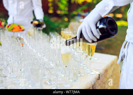 Barkeeper in weißen Handschuhen Champagner in Gläser gießen. Stockfoto