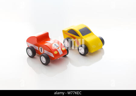Rote und gelbe kleine Spielzeugautos auf weißem Hintergrund Stockfoto
