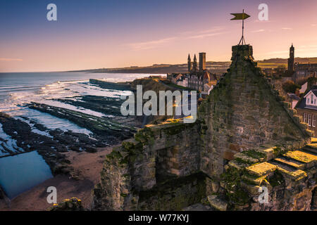 Eine atemberaubende Aussicht auf den Sonnenuntergang von der Spitze der St Andrews Burgruinen zu den Ruinen der Kathedrale und der Pier. Stockfoto