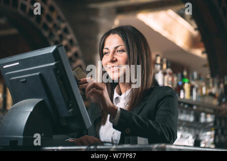 Kleine Unternehmen, Menschen- und Servicekonzept - glückliche Frau oder Kellner oder Manager im Vorfeld des Zählers mit Kasse Stockfoto