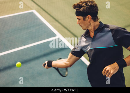 Professional tennis player schlagen Vorhand auf Hartplatz. Junge Mann in Sportkleidung spielen Tennis auf dem Tennisplatz. Stockfoto