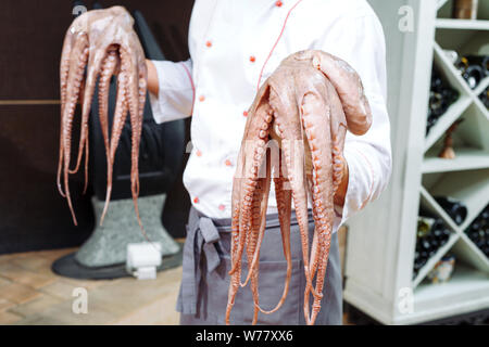 Der Koch ist Holding und Köche einen Oktopus. Stockfoto