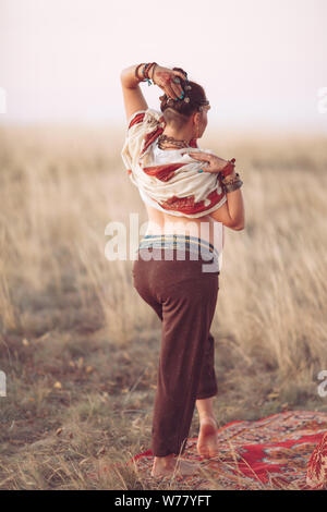 Konzept. Frau spielen eine Klangschale. Schwangeren Yoga im Feld bei Sonnenuntergang Stockfoto