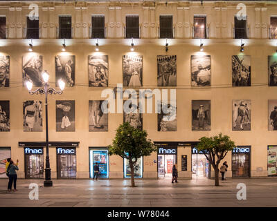 Eine breite Straße mit tramtracks, die Fnac Shop und Menschen waling in der Nacht in der Altstadt von Sevilla, Spanien Stockfoto