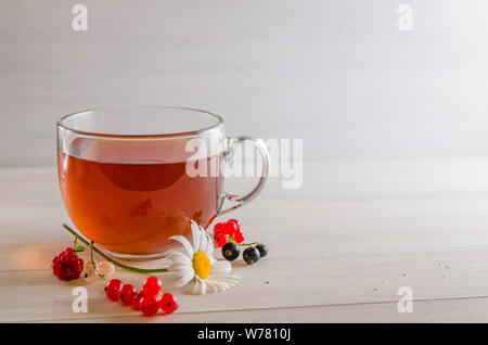 Tee in eine Tasse mit Beeren und Kamille auf weißem Hintergrund mit Kopie Raum Stockfoto