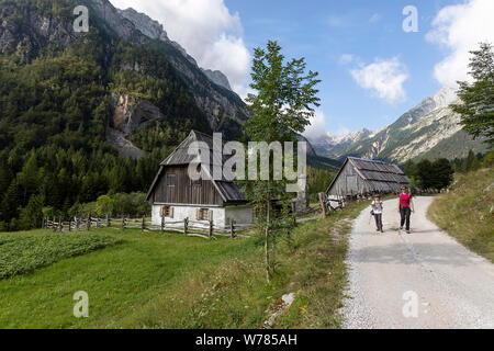 Mutter und Sohn gehen auf Schotterpiste durch alte, traditionelle Hütten im Soca Tal, Bovec, Slowenien, Europa Stockfoto