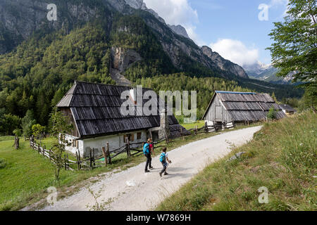 Mutter und Sohn gehen auf Schotterpiste durch alte, traditionelle Hütten im Soca Tal, Bovec, Slowenien, Europa Stockfoto