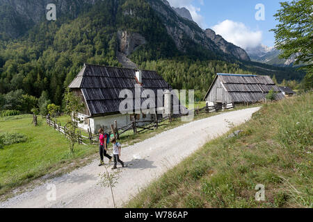 Mutter und Sohn gehen auf Schotterpiste durch alte, traditionelle Hütten im Soca Tal, Bovec, Slowenien, Europa Stockfoto